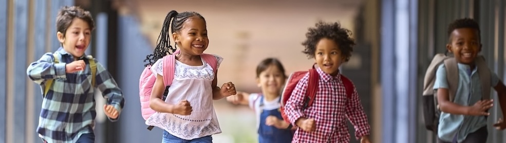 photo of five young schoolchildren with backpacks running